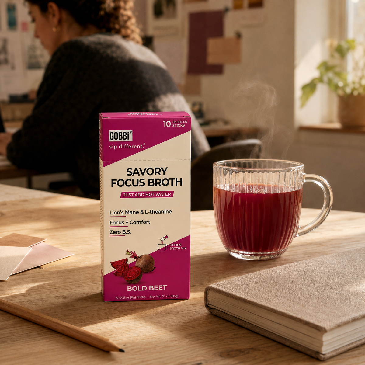 Bold Beet Focus Broth beside a creative studio workspace
